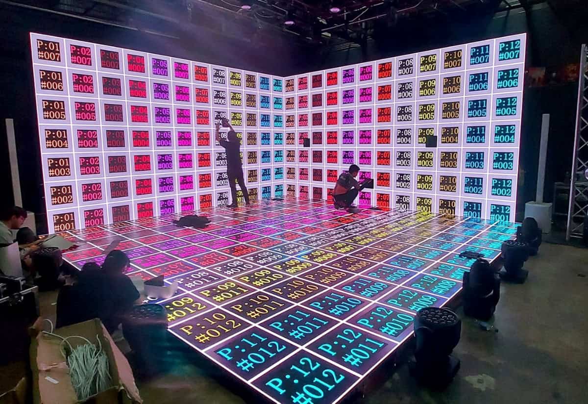 Vibrant DJ or event stage with LED screens displaying colorful grid patterns, perfect for digital projection mapping and creative event production.
