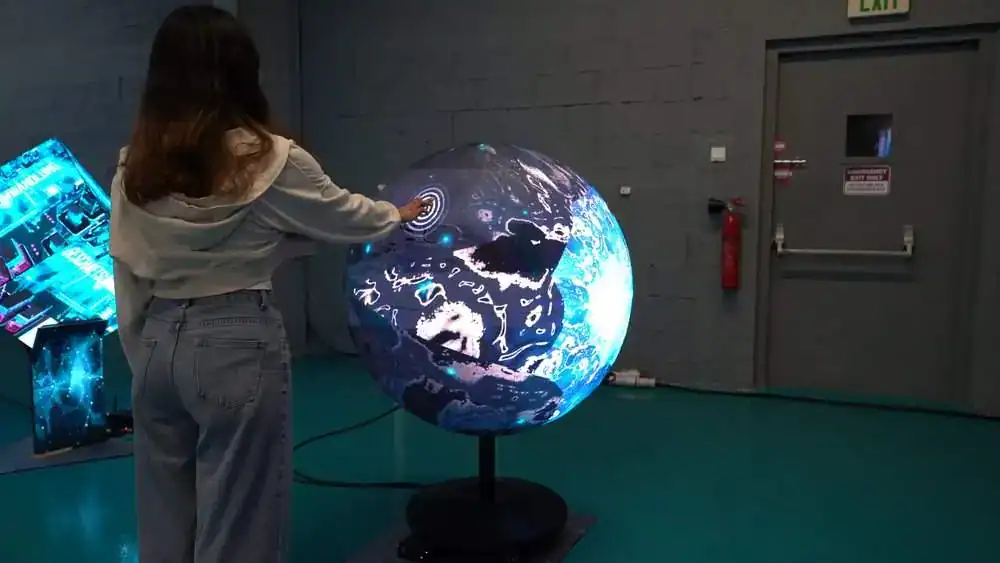 Vivid digital globe interaction with futuristic touchscreen display at TriVision Studios, showcasing innovative visual technology for immersive experiences and multimedia production.