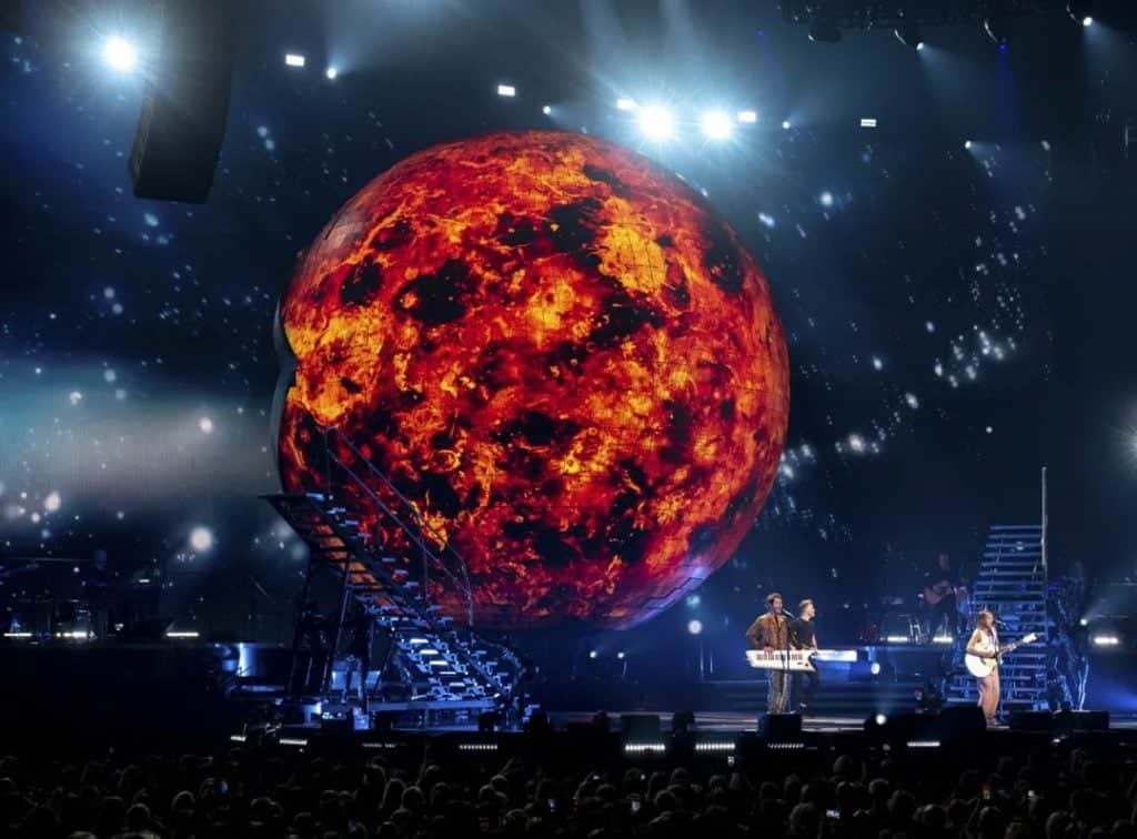 Vivid stage lighting and a huge fiery Mars projection create an immersive concert experience at TriVision Studios, showcasing advanced visual production and multimedia entertainment.
