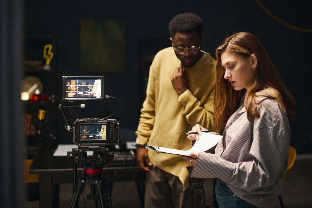 1. Behind-the-scenes of a professional video production at TriVision Studios, featuring filmmakers setting up shot with camera, lights, and script for high-quality content creation.