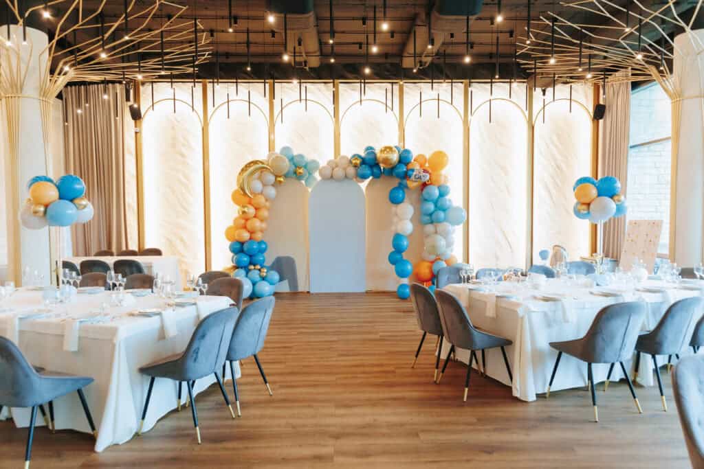Brightly lit event space with balloon decor, elegant tables, and modern design for parties or special events. Scenic, festive atmosphere perfect for memorable gatherings.