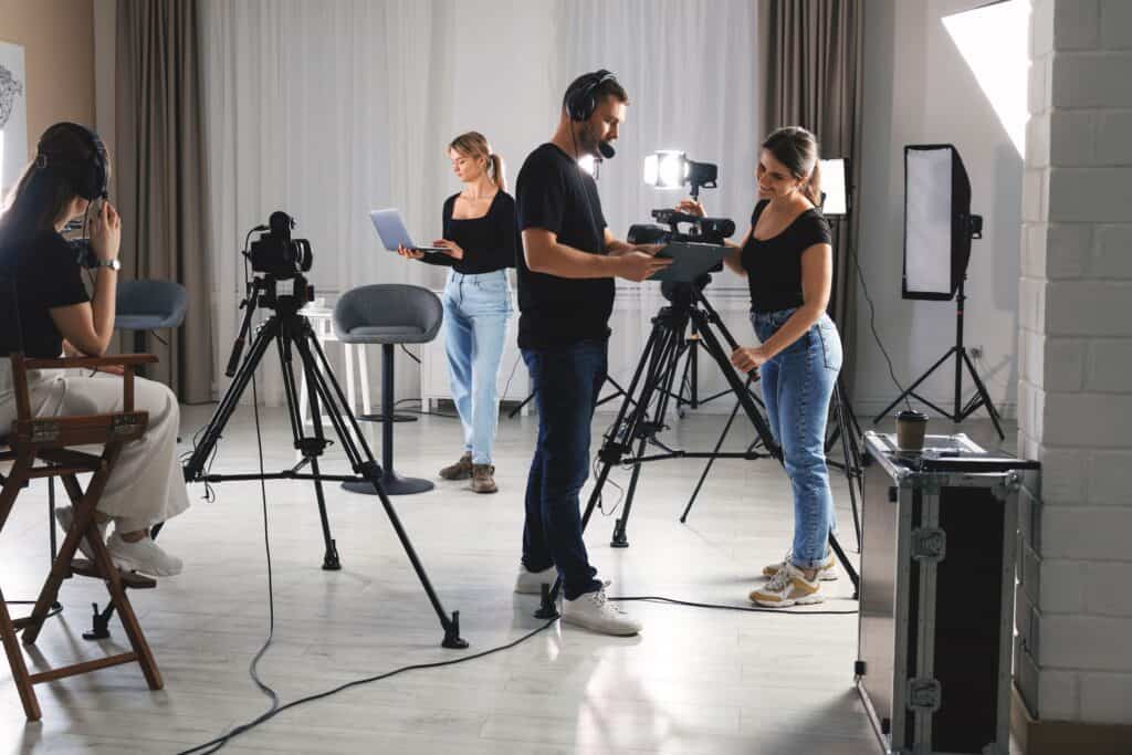 Film production crew working with cameras and lighting in a modern studio environment for creative video projects.