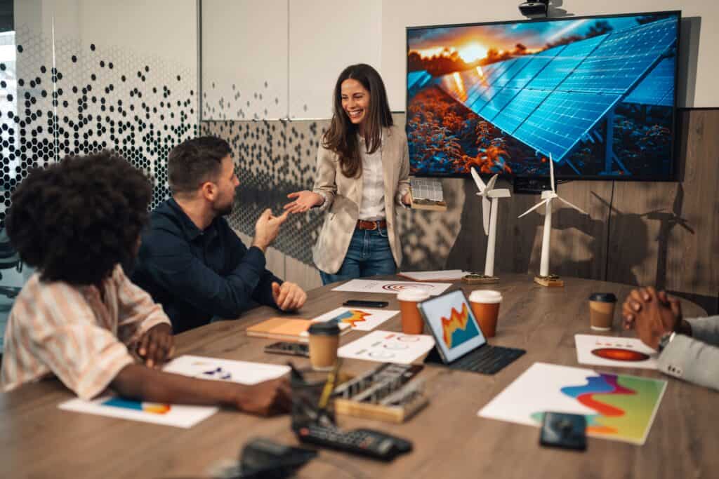 High-resolution image of a professional presentation on solar power and wind energy innovation at TriVision Studios, showcasing a team discussing sustainable energy projects with visual aids and eco-friendly technology.