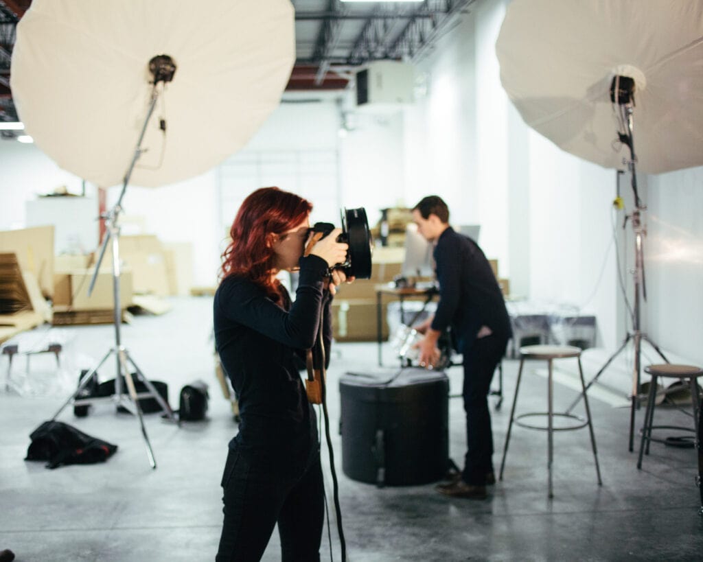 Professional videographer capturing footage with advanced camera gear in a well-lit studio environment.