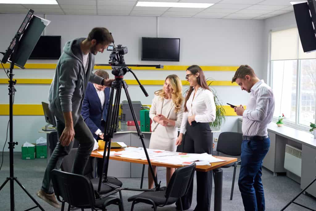 Professional video production team working together in a studio with camera equipment, lights, and monitors for high-quality video content creation.
