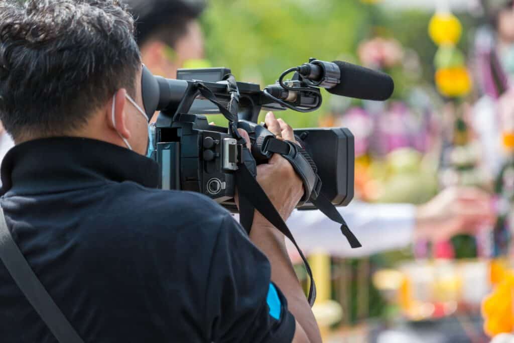 Professional videographer filming outdoors with a professional camera during a live event, capturing high-quality footage for corporate or event videos.