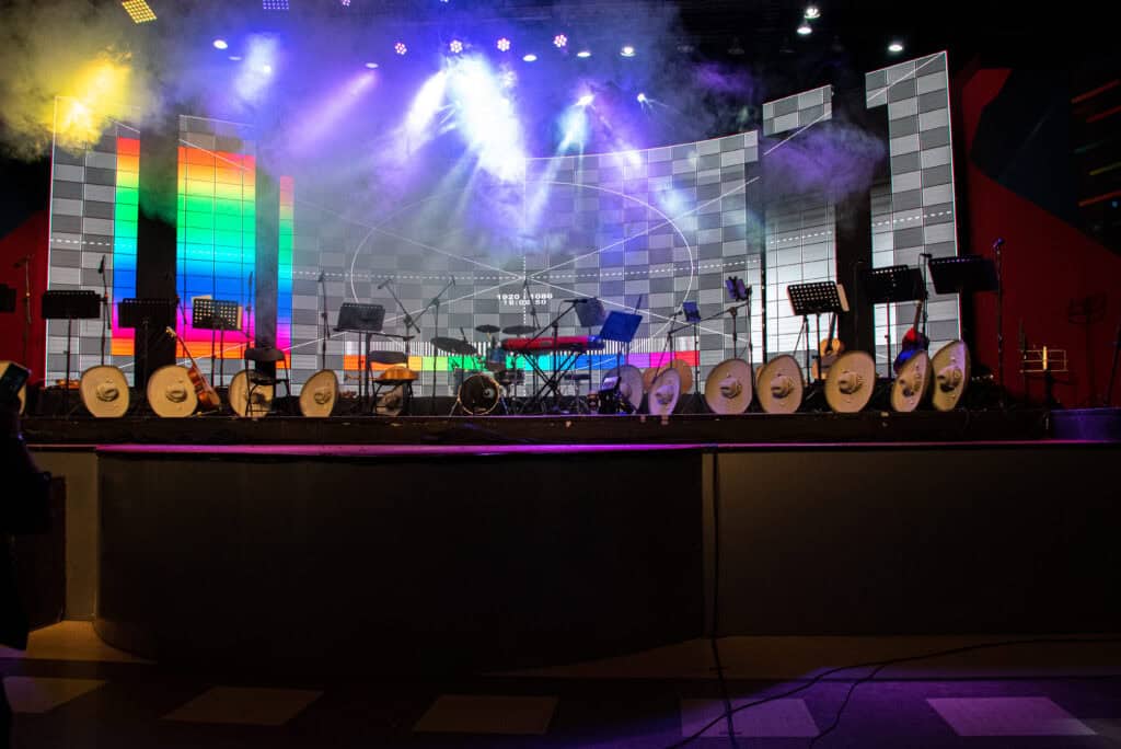 An illuminated stage with colorful lighting effects, musical instruments, and electronic equipment ready for a live performance or event.
